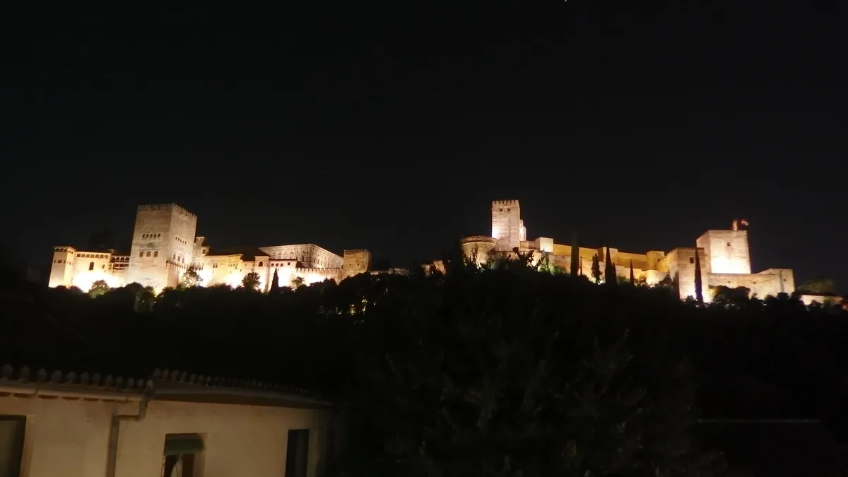 A Alhambra iluminada à noite na crista do morro, vista do Albaicín, com a torre de Comares ao centro
