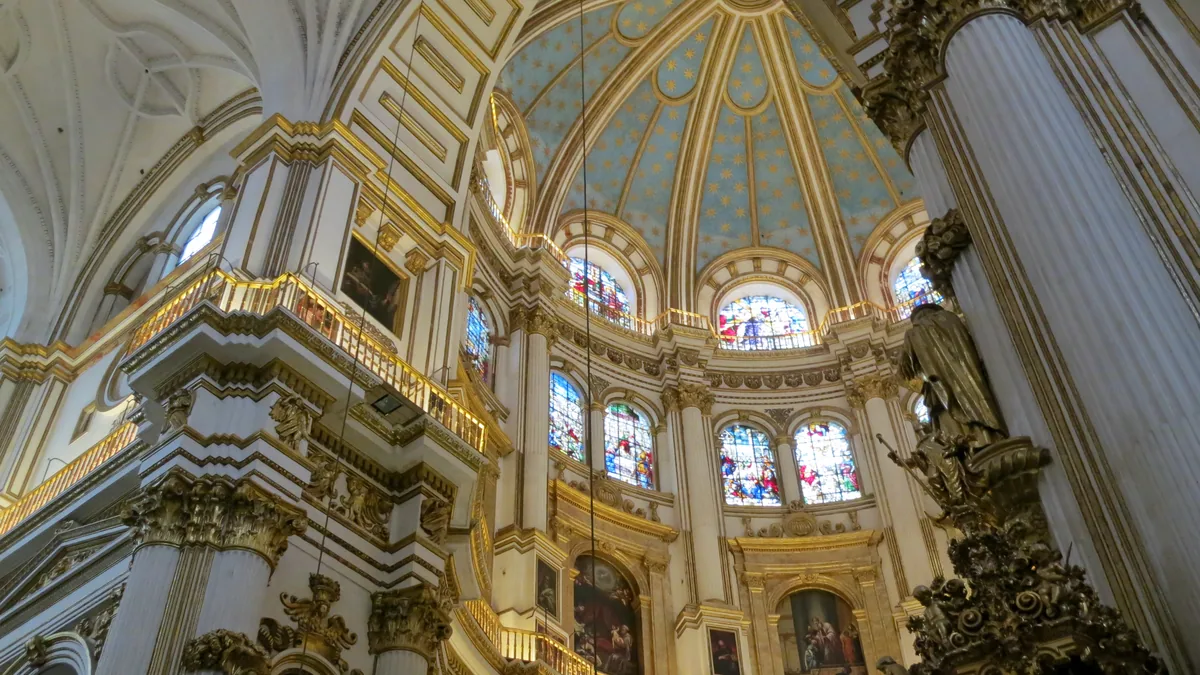 O interior branco e dourado da Capilla Mayor da Catedral de Granada, com a cúpula e os vitrais altos