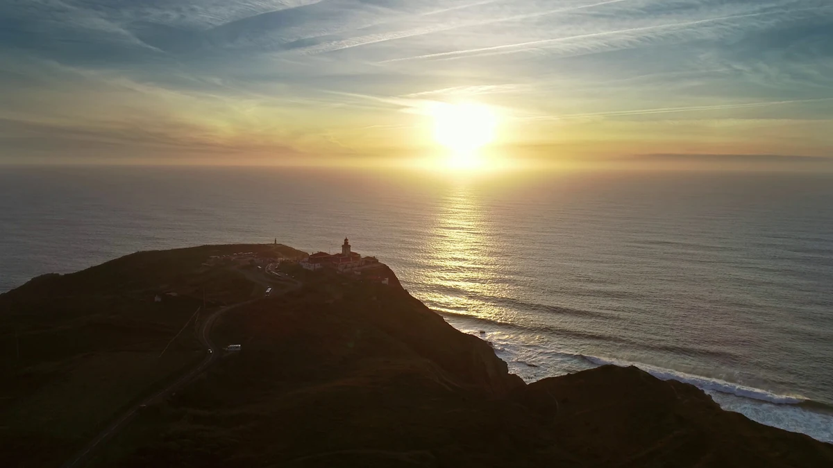 Promontório do Cabo da Roca ao pôr do sol, com o farol no alto e o Atlântico à frente