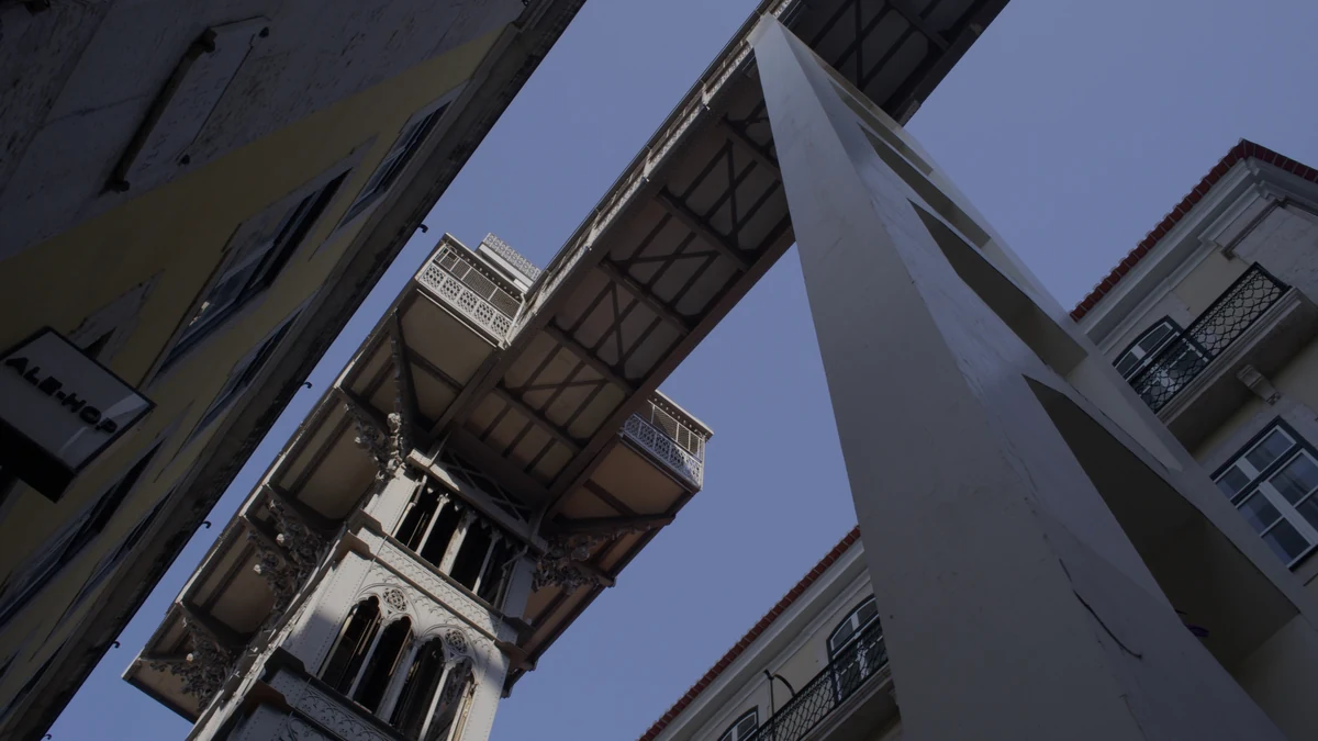 Estrutura de ferro do Elevador de Santa Justa vista de baixo, entre prédios da Baixa