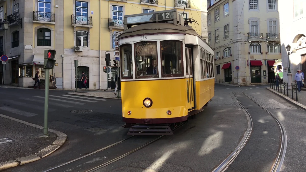 Elétrico amarelo numa rua estreita da cidade velha de Lisboa