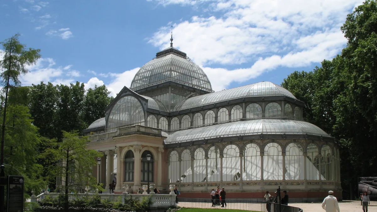 O Palacio de Cristal no Parque del Retiro, estufa de ferro e vidro com cúpula central, cercada de árvores