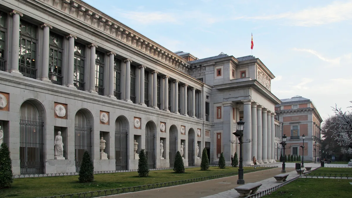 A fachada do edifício Villanueva, sede do Museo del Prado, com a colunata jônica estendida ao longo do Paseo del Prado em luz de fim de tarde