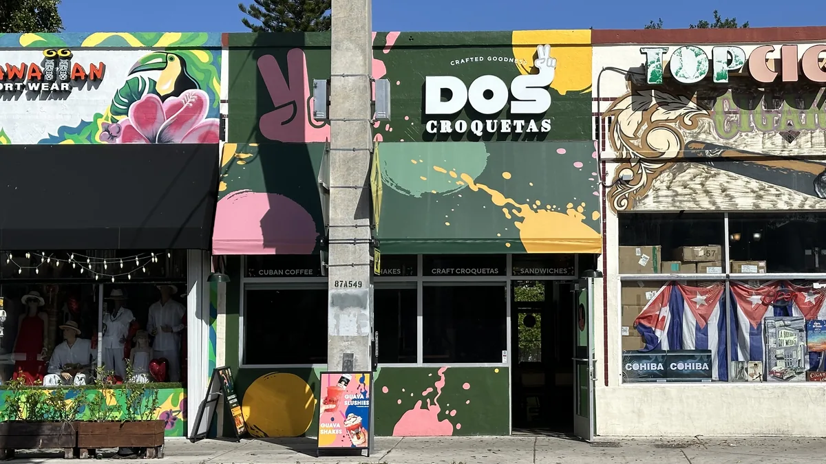 Uma fachada de comércio na Calle Ocho, em Little Havana, com mural colorido e bandeiras cubanas sobre a porta