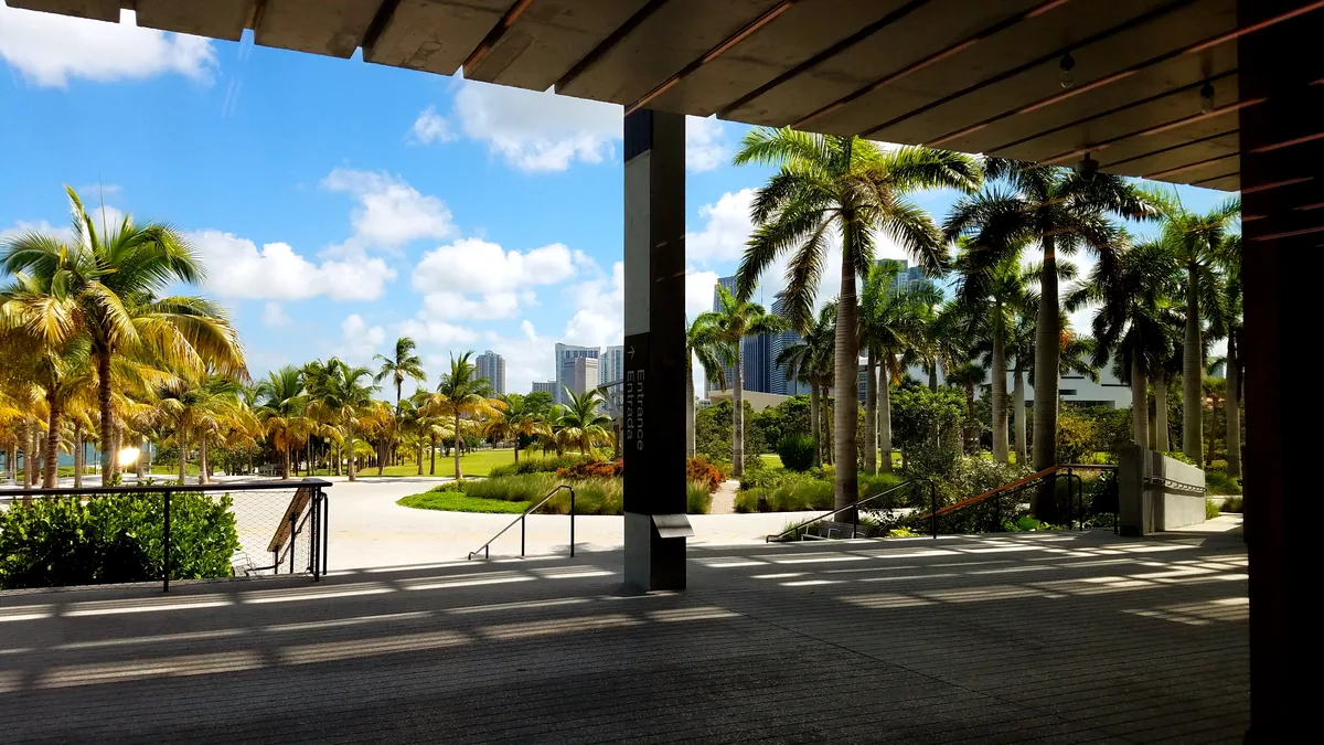 A varanda coberta do Pérez Art Museum Miami, com as colunas do beiral, as palmeiras do parque e o skyline da cidade ao fundo
