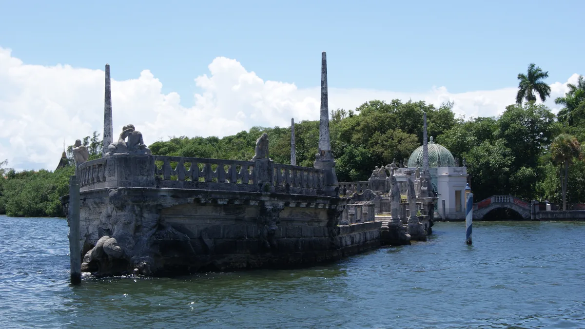 A barca de pedra de Vizcaya na Baía de Biscayne, com as esculturas na balaustrada e a vegetação da villa ao fundo
