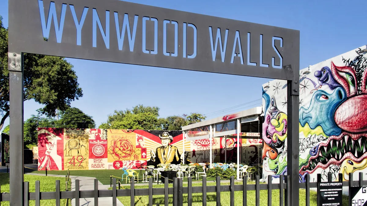 O pórtico de entrada do Wynwood Walls, com o nome em letras altas sobre a estrutura e os murais coloridos do recinto atrás