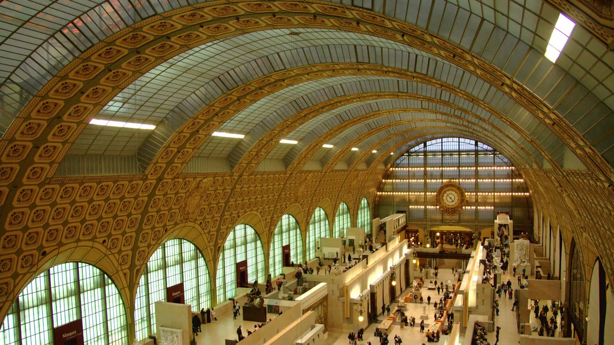 A nave do Musée d’Orsay, antiga estação de trem, com o teto abobadado de vidro e ferro e as esculturas no piso
