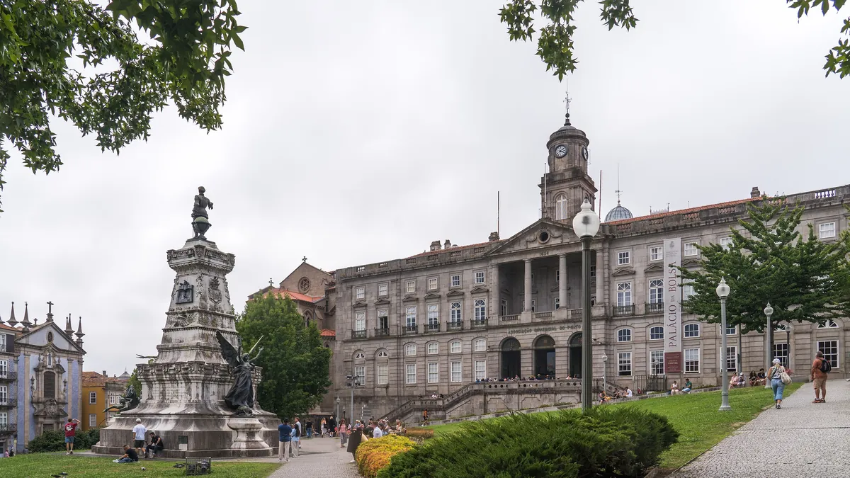 Fachada neoclássica do Palácio da Bolsa vista da praça, com o monumento ao Infante Dom Henrique em primeiro plano