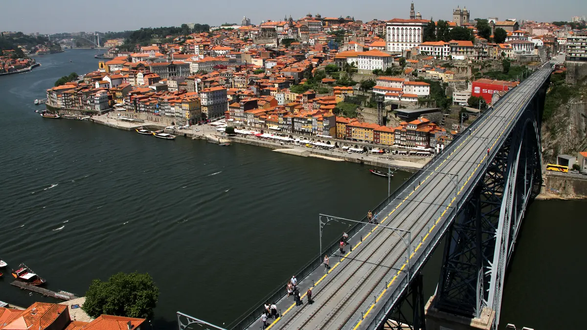 A Ponte Dom Luís I sobre o Douro, com o tabuleiro inferior em primeiro plano e a cidade do Porto subindo a encosta ao fundo