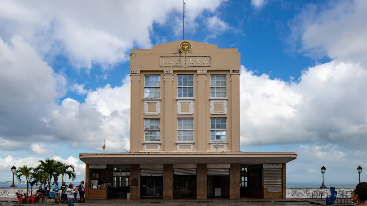 A torre do Elevador Lacerda vista da Cidade Alta, com o relógio no topo e palmeiras ao lado da praça