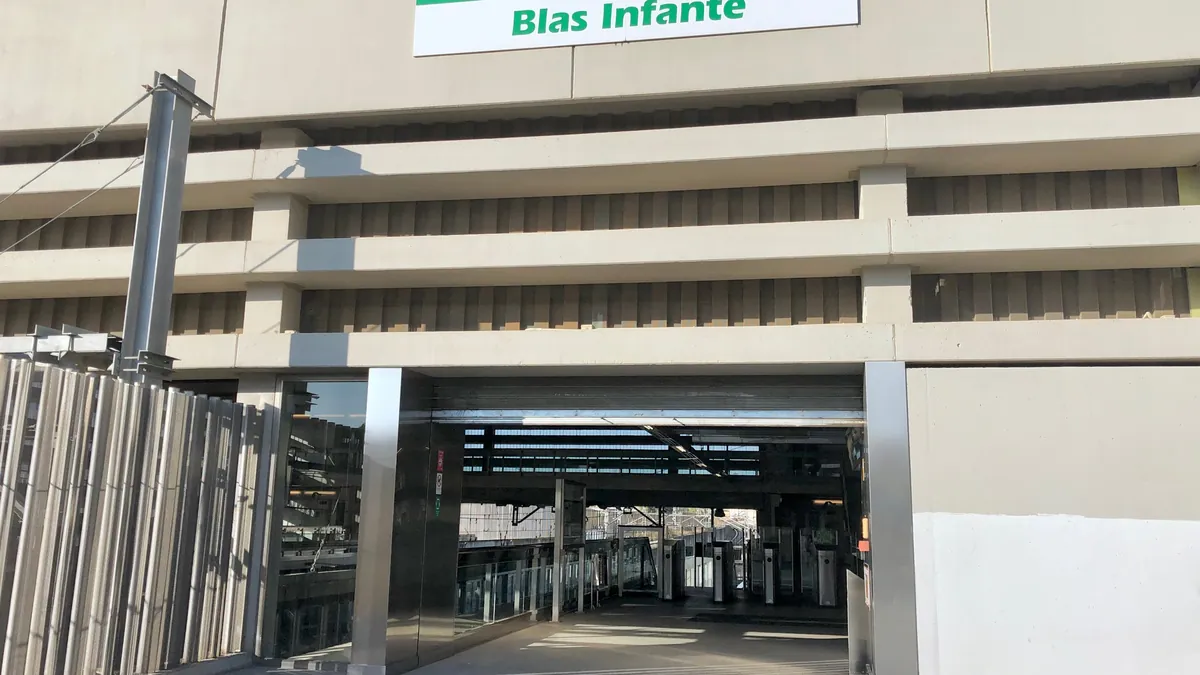 Entrada da estação Blas Infante do Metro de Sevilha, com a fachada em concreto e o letreiro verde