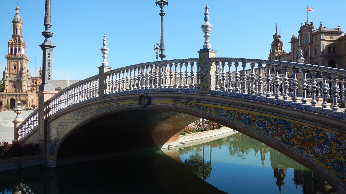 Uma das pontes de azulejo da Plaza de España sobre o canal, com a balaustrada branca refletida na água